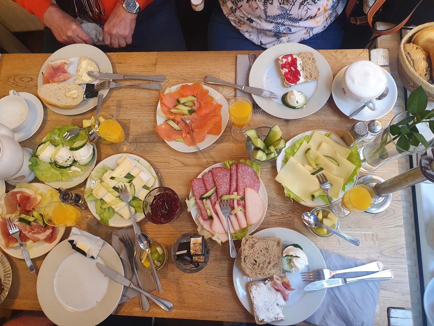 Gedeckter Frühstückstisch mit Kannen, Marmelade, Brötchenkorb und einer Kerze.