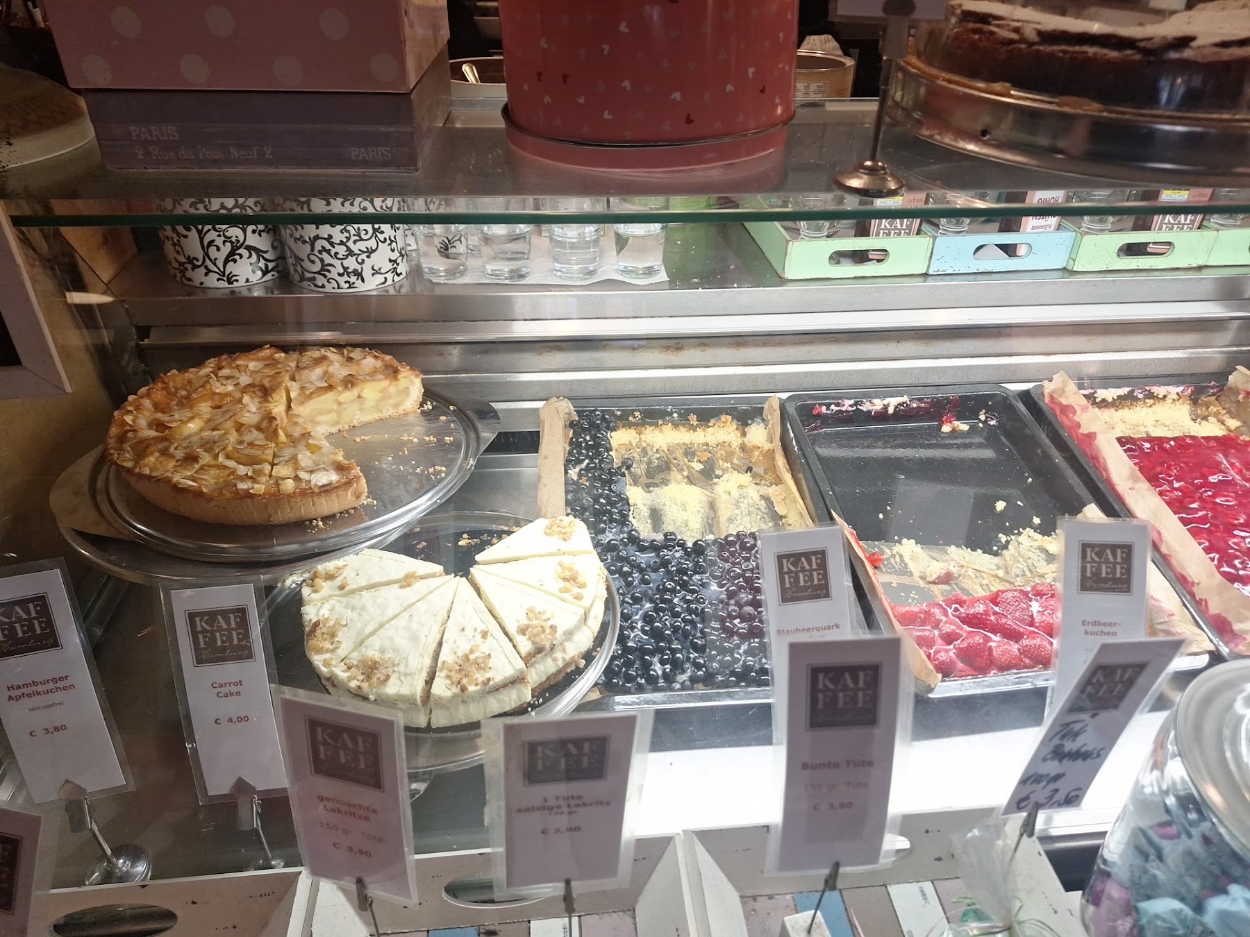 Die Kuchentheke mit Apfelkuchen, Carrot Cake, Blaubeerquark und Erdbeerkuchen, davor kleine Preisschilder.